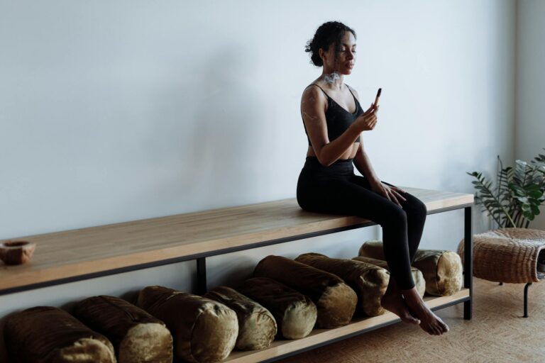 Woman in active wear meditating at home with palo santo, embracing a healthy lifestyle.